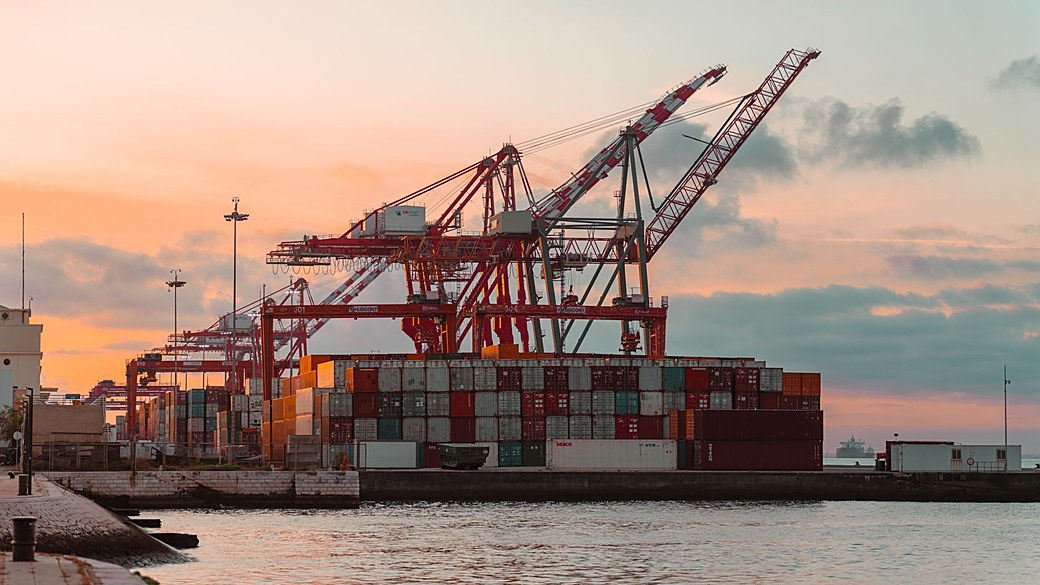 Port crane loading containers at sunset