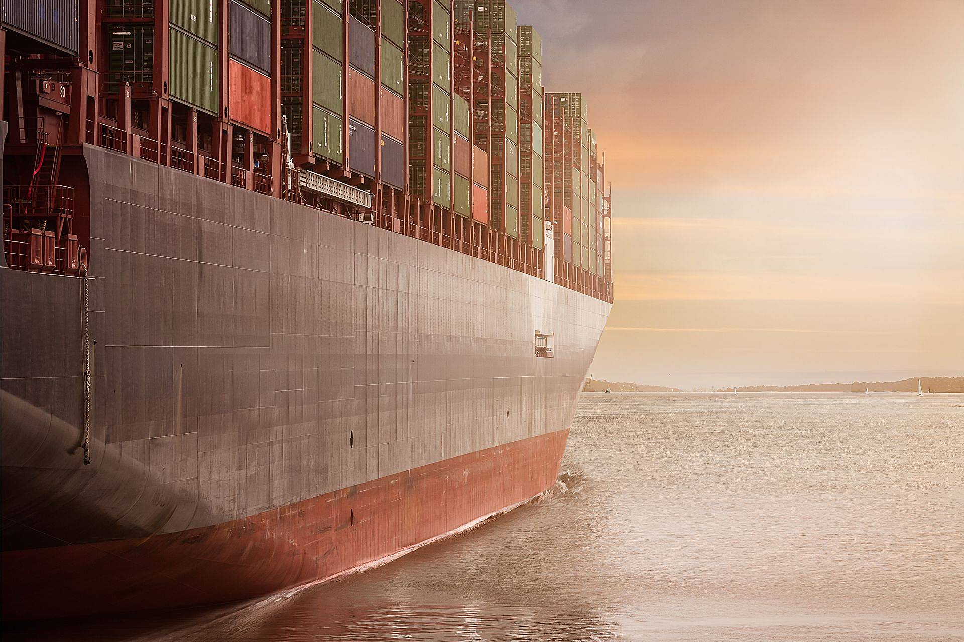 Cargo containers stacked at a busy ocean port with a container ship at berth